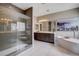 Modern bathroom featuring a glass shower, double vanity, and soaking tub with elegant gray tile at 11342 Early Sun Ct, Las Vegas, NV 89135