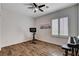 Bright bedroom featuring hardwood floors, ceiling fan, window with shutters, and a modern stationary bicycle at 11342 Early Sun Ct, Las Vegas, NV 89135