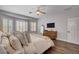 Comfortable main bedroom with wood floors, a large window, dresser with mounted tv, and neutral color palette at 11342 Early Sun Ct, Las Vegas, NV 89135