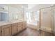 Bright bathroom featuring double sinks, a soaking tub, a separate shower, and large windows at 124 Countrywood Cir, Las Vegas, NV 89107