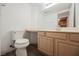 Bathroom featuring a oak vanity with cabinets, a large mirror, and a toilet with water-efficient fixtures at 124 Countrywood Cir, Las Vegas, NV 89107