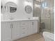 Bathroom features double sinks, white cabinetry, a frameless shower, and plank flooring at 1677 Balsam Mist Ave, Las Vegas, NV 89183