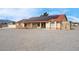 Charming single-story home featuring a red tile roof and solar panels on a gravel lot, under a bright blue sky at 1800 Red Rock Dr, Pahrump, NV 89048