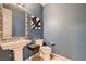 Stylish powder room with modern fixtures, a pedestal sink, and a bold blue accent wall at 261 Crimson Edge St, Henderson, NV 89012