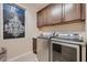 Well-lit laundry room with stainless steel washer and dryer, dark cabinets, and a modern light fixture at 261 Crimson Edge St, Henderson, NV 89012