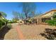 Large backyard with mature shade tree, neutral rock ground cover, and brick walkway at 3021 Lotus Hill Dr, Las Vegas, NV 89134