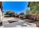 Private backyard with desert landscaping, mature trees, and a brick accent wall at 4137 Cackling Goose Dr, North Las Vegas, NV 89084