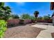 Private backyard with desert landscaping, mature trees, a brick accent wall, and stone ground cover at 4137 Cackling Goose Dr, North Las Vegas, NV 89084