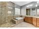 Luxurious bathroom featuring a glass-enclosed shower, soaking tub, and double vanity sinks at 4137 Cackling Goose Dr, North Las Vegas, NV 89084