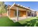 This exterior shows a covered patio with sliding glass doors and lush artificial turf in the backyard at 437 Via Stretto Ave, Henderson, NV 89011