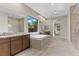 Sunlit bathroom with a large soaking tub, walk-in shower, and dual vanities, with outside view at 47 Garibaldi Way, Henderson, NV 89011