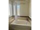 Bathroom featuring a large soaking tub surrounded by tile and a window with white blinds at 4704 Obannon Dr # D, Las Vegas, NV 89102