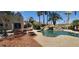 Scenic backyard featuring a pristine pool with rock waterfall, a fire pit, and palm trees at 5312 Manuel Dr, Las Vegas, NV 89149