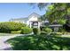 Well-manicured front yard with lush green grass, mature trees and manicured bushes at 5860 N Campbell Rd, Las Vegas, NV 89149