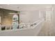 Upstairs hallway with white railing overlooking the living room's stone accent wall and large windows at 5860 N Campbell Rd, Las Vegas, NV 89149
