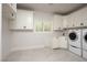 Spacious laundry room with white cabinets, tile floor, and modern washer and dryer units at 5860 N Campbell Rd, Las Vegas, NV 89149