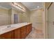 Well-lit bathroom with double sinks, wood cabinets, and a glass-enclosed shower at 7556 Wingspread St, North Las Vegas, NV 89084