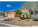 Single-story home featuring a two-car garage and desert-style landscaping with gravel, rocks, and native plants at 7556 Wingspread St, North Las Vegas, NV 89084