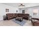 Comfortable living room with a large brown sectional sofa, tile flooring, and a ceiling fan at 7641 Lani Dawn St, Las Vegas, NV 89149