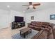 Cozy living room with a large brown sectional sofa, a ceiling fan, and tile flooring at 7641 Lani Dawn St, Las Vegas, NV 89149