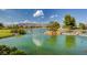 Scenic pond view featuring a rock waterfall, island with lush trees, and serene waters, creating a peaceful outdoor setting at 7760 Pine Warbler Way, North Las Vegas, NV 89084
