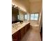 Bathroom with dual sinks, vanity, garden tub beneath the window, tiled floors, and a bright vanity mirror at 7821 Desert Bell Ave, Las Vegas, NV 89128