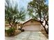 Inviting home exterior with a well-manicured lawn, mature trees, and a spacious two-car garage providing ample parking at 7821 Desert Bell Ave, Las Vegas, NV 89128