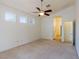 Bright bedroom featuring neutral carpet, a ceiling fan, and a connecting door to the hallway at 8249 Jo Marcy Dr, Las Vegas, NV 89131