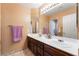 Well-lit bathroom featuring double sinks with dark wood cabinets and a large mirror at 8277 Mount Nido Dr, Las Vegas, NV 89147