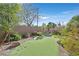 Private backyard featuring artificial turf, desert landscaping, and mature trees at 9008 Sawhill Pond St, Las Vegas, NV 89131