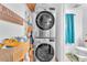 Convenient laundry area with stacked washer and dryer, a sign, storage basket and access to the half bathroom at 9958 Fragile Fields St, Las Vegas, NV 89183