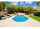 Serene backyard with a blue pool, patio area, lush landscaping, and comfortable lounge seating at 11244 Playa Caribe Ave, Las Vegas, NV 89138