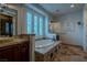 This bathroom includes a tiled jacuzzi tub, stone floors, stone countertops, and plenty of natural light at 11814 Canons Brook Dr, Las Vegas, NV 89141