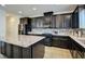 Modern kitchen boasts dark cabinetry, stainless steel appliances, granite countertops, and a large island at 12391 Pinetina St, Las Vegas, NV 89141