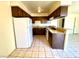 Bright kitchen with white refrigerator, wood cabinets, tiled floor, and bar top at 1524 Henry Dr, Las Vegas, NV 89110