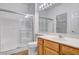 Well-lit bathroom with glass shower doors, wood vanity, and ceramic tile floors at 2099 Desert Woods Dr, Henderson, NV 89012
