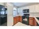 Functional kitchen featuring granite counters, a gas range, a black fridge, and white and orange cabinets at 3125 N Buffalo Dr # 1133, Las Vegas, NV 89128