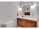 Half bathroom features a wood vanity, a white countertop, an arched mirror, and modern lighting fixtures at 4651 Munich Ct, Las Vegas, NV 89147