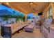 Covered patio with stylish seating, a fire pit, a built-in grill, and ambient lighting at 4651 Munich Ct, Las Vegas, NV 89147