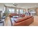Open living room with a ceiling fan, views from windows, hardwood floors and a cozy kitchen in the background at 4820 Se Clifftop Dr, Pahrump, NV 89061