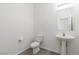 Clean half bathroom features a pedestal sink, toilet, and modern lighting fixtures at 5317 Golden Melody Ln, North Las Vegas, NV 89081