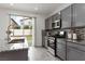 Well-lit kitchen featuring gray cabinets, granite countertops, stainless steel appliances, and access to the backyard at 5317 Golden Melody Ln, North Las Vegas, NV 89081