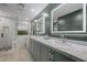 Bathroom featuring dual sinks with marble countertops and illuminated mirrors at 5594 Trilling Bird Dr, Las Vegas, NV 89135
