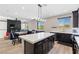 Bright open-concept kitchen with dark cabinets, stainless steel appliances, and an island with a marble countertop at 5594 Trilling Bird Dr, Las Vegas, NV 89135