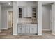 Stylish gray dry bar featuring granite countertops and glass shelving, adding elegance to the home at 7095 Falabella Ridge Ave, Las Vegas, NV 89131