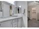 Well-lit bathroom showcases a double-sink vanity, stone countertops, and an entrance to the Primary suite at 7095 Falabella Ridge Ave, Las Vegas, NV 89131