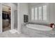 Bright bathroom with white soaking tub, plantation shutters, granite detail, and walk-in closet at 7095 Falabella Ridge Ave, Las Vegas, NV 89131