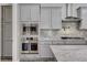 Close-up of the kitchen featuring stainless steel appliances, gray cabinets, marble countertops, and a gas range at 7095 Falabella Ridge Ave, Las Vegas, NV 89131