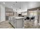 Open-concept kitchen with marble countertops, gray cabinets, stainless steel appliances, and views of the living and dining areas at 7095 Falabella Ridge Ave, Las Vegas, NV 89131