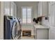 Bright laundry room with modern washer and dryer, window with shutters, granite countertop, and convenient shoe storage at 7095 Falabella Ridge Ave, Las Vegas, NV 89131